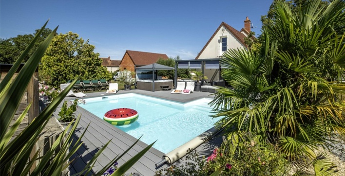 Photo d'une piscine Aquilus et d'un spa familial dans un jardin luxuriant à Bourges, transformé en havre de paix