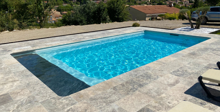 Une piscine coque avec volet automatique sous plage signée Piscines Ibiza