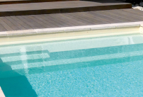 La piscine coque à fond plat avec banquette et repose coude et repose pieds